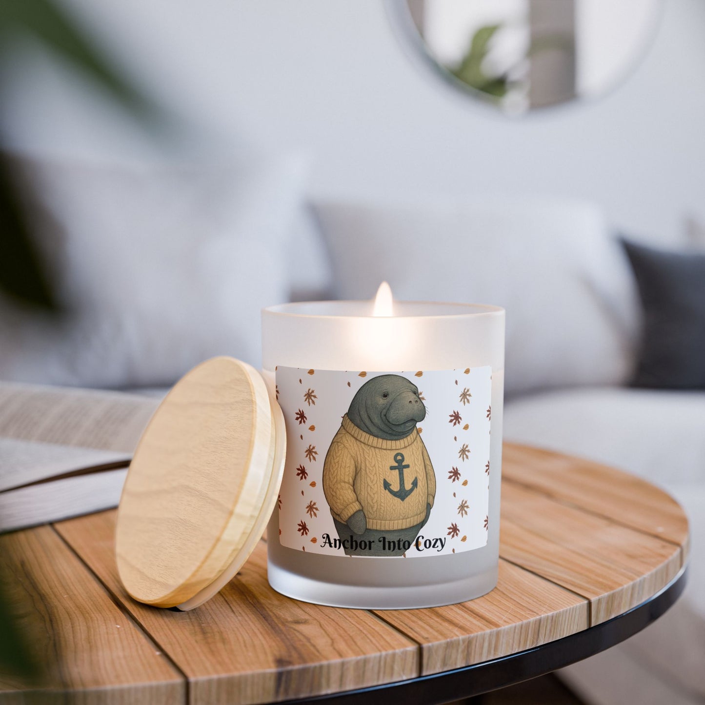 Candle with a label featuring a seal in a sweater on a wooden table.