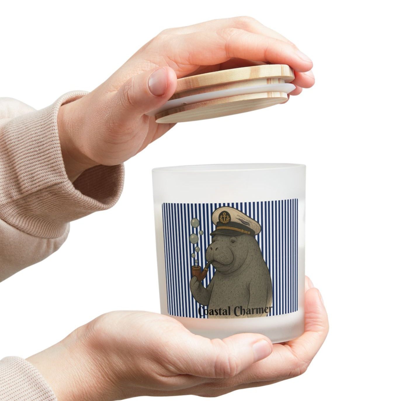 Person holding a candle with a design on the label against a white background