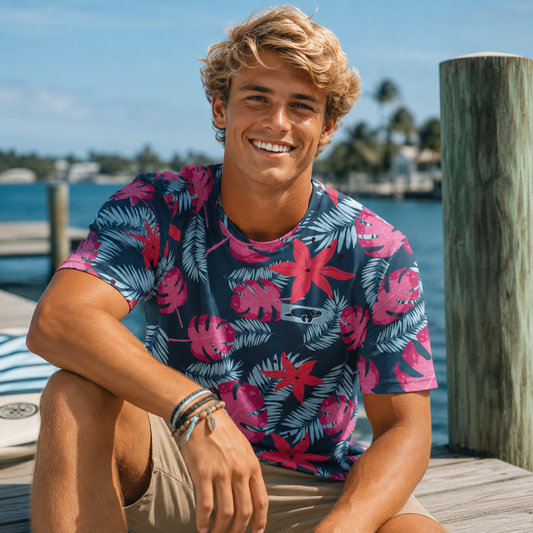 Man wearing a colorful tropical shirt sitting by a dock with water and sky in the background