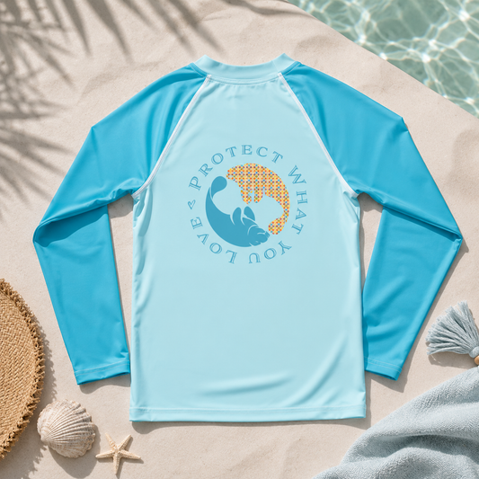 Blue long-sleeve shirt with a graphic design on a sandy surface near water