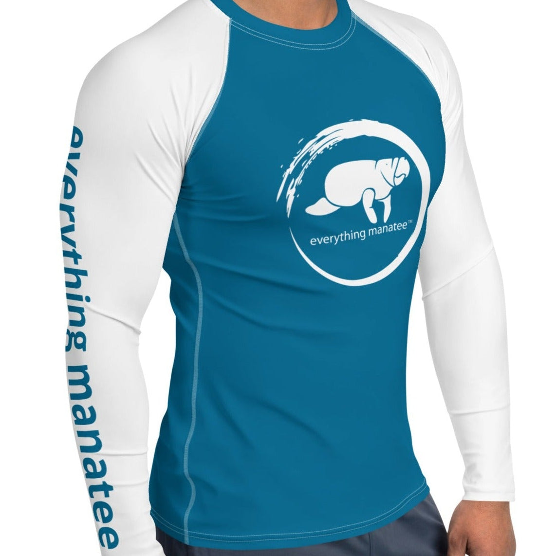 A man wearing a teal and white long-sleeve rash guard with a white manatee logo on the chest and 'everything manatee' printed down one sleeve, shown against a plain white background.