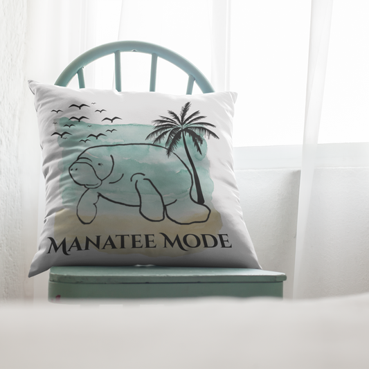 Decorative pillow with a manatee design and 'Manatee Mode' text on a white couch.