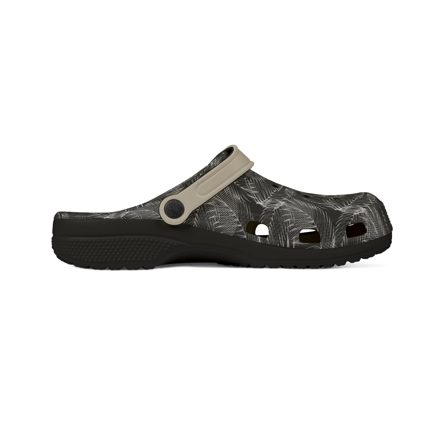 A single clog-style sandal shown in side profile on a plain white background. The upper is black with a light gray leaf pattern, and the strap is a light beige/tan color with a dark snap button.