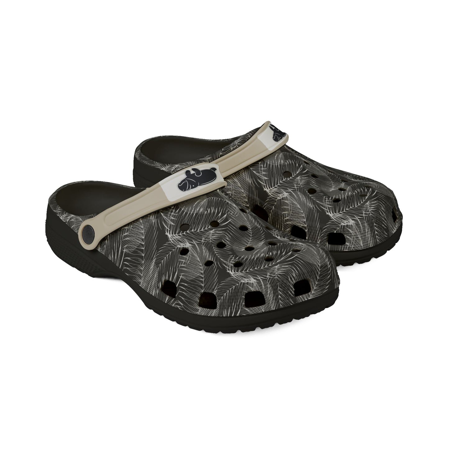 A pair of Croc-style clogs with a black and gray palm leaf pattern, featuring a beige strap with a black logo.