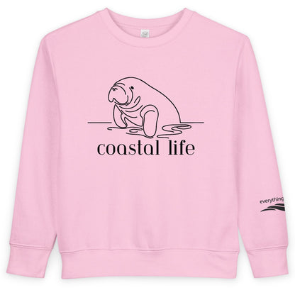 Pink sweatshirt with a manatee graphic and 'coastal life' text on a white background