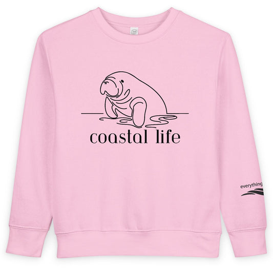 Pink sweatshirt with a manatee graphic and 'coastal life' text on a white background