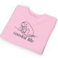 Pink sweatshirt with 'coastal life' and seal graphic on a white background
