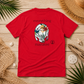 A red short-sleeve t-shirt laid flat on a light wood surface, surrounded by beach-themed props including palm leaves, a straw hat, driftwood, and seashells. The shirt features a central graphic of a white cat face decorated with tropical flowers and the words 'everything' above and 'manatee' below.