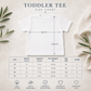 Toddler Tee size chart graphic showing a white short-sleeve T-shirt with arrows indicating width and length, plus a size table and cotton product features on a light neutral background with leaf props.