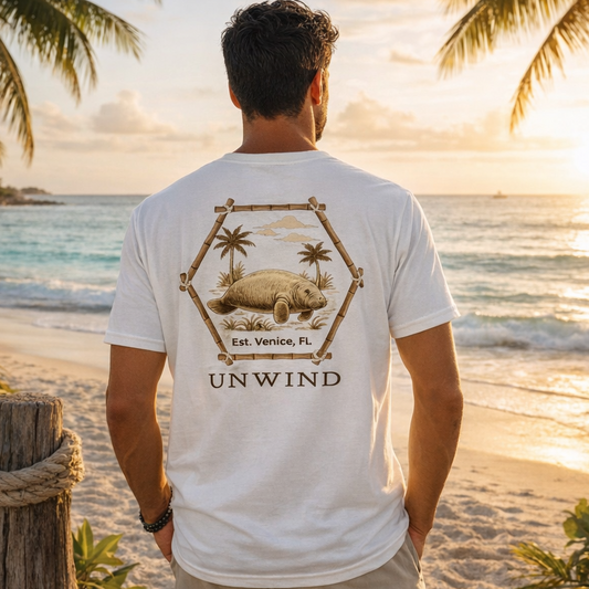 Man wearing a 'UNWIND' t-shirt with a beach design on a tropical beach at sunset.