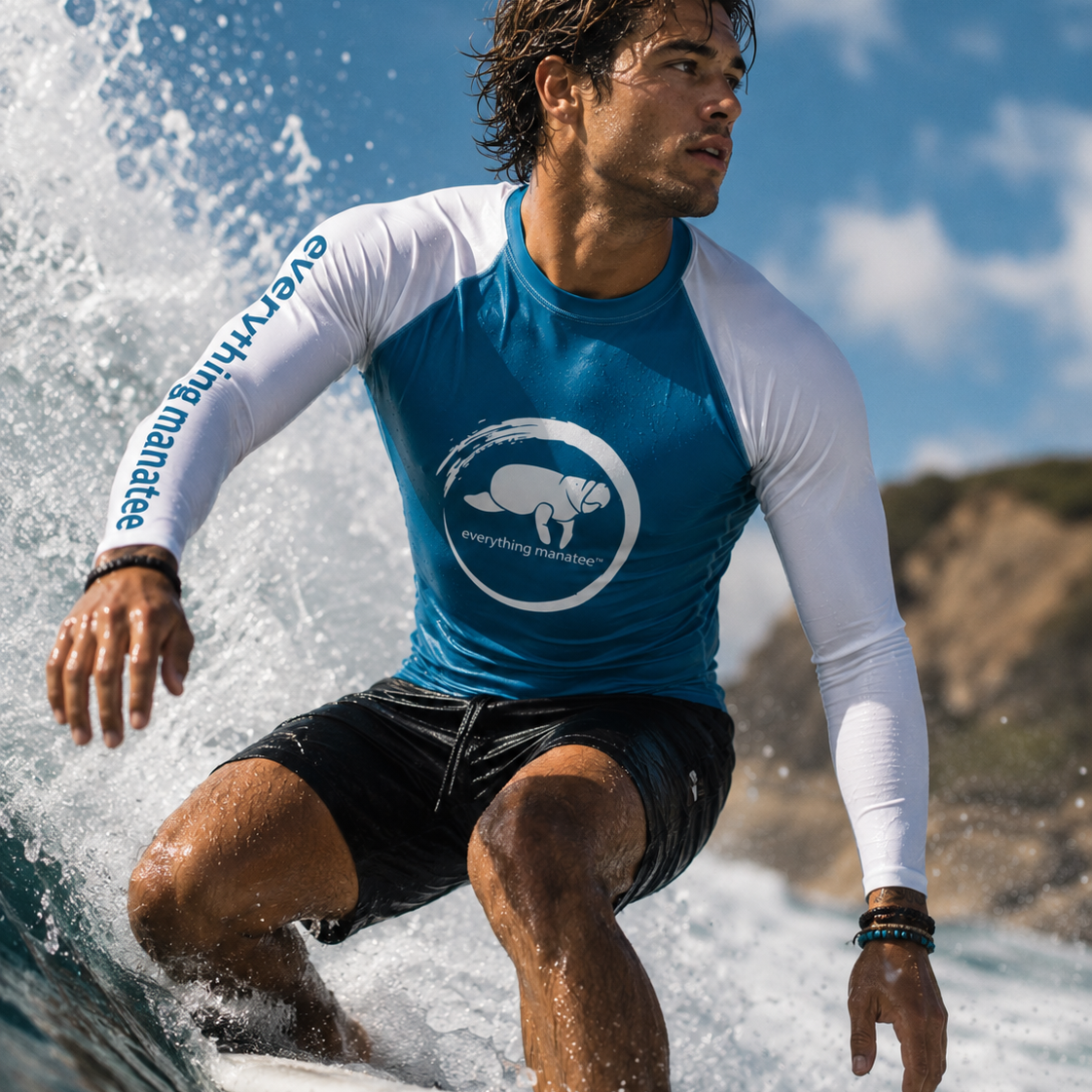 A man surfing on a wave wearing a blue and white long-sleeve rash guard with a polar bear logo and 'everything marine' text, along with black swim shorts.