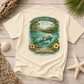 A cream-colored short-sleeve t-shirt with a large vintage-style graphic on the back. The graphic features a manatee in turquoise water with the text 'DRIFT & DREAM' and 'FLORIDA WATERS'.