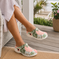 Person wearing floral clogs on a porch with ocean view