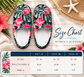 A size chart graphic for women's slippers, showing a pair of floral slipper tops above a size table. The slippers have a navy blue tropical leaf pattern with pink hibiscus flowers.
