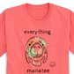 A close-up view of the front print design of the Coral Palms Manatee T-Shirt, depicting a colorful and playful manatee with tropical flowers and plants around it.