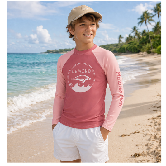 Child wearing a pink long-sleeve shirt with a logo on a beach