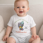Baby wearing a white onesie with paddleboarding design and text
