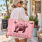 A woman wearing sunglasses and a white shirt carries a large pink tote bag with a manatee illustration and palm leaf pattern in an outdoor storefront setting.