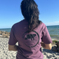 Lifestyle shot of a woman wearing Midnight Grape Manatee Wave T-Shirt from the back, showing relaxed fit and clean finished sleeve cuffs and hem.