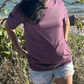 Lifestyle shot of a woman wearing Midnight Grape Manatee Wave T-Shirt from the front, featuring a playful manatee and unique wave design.