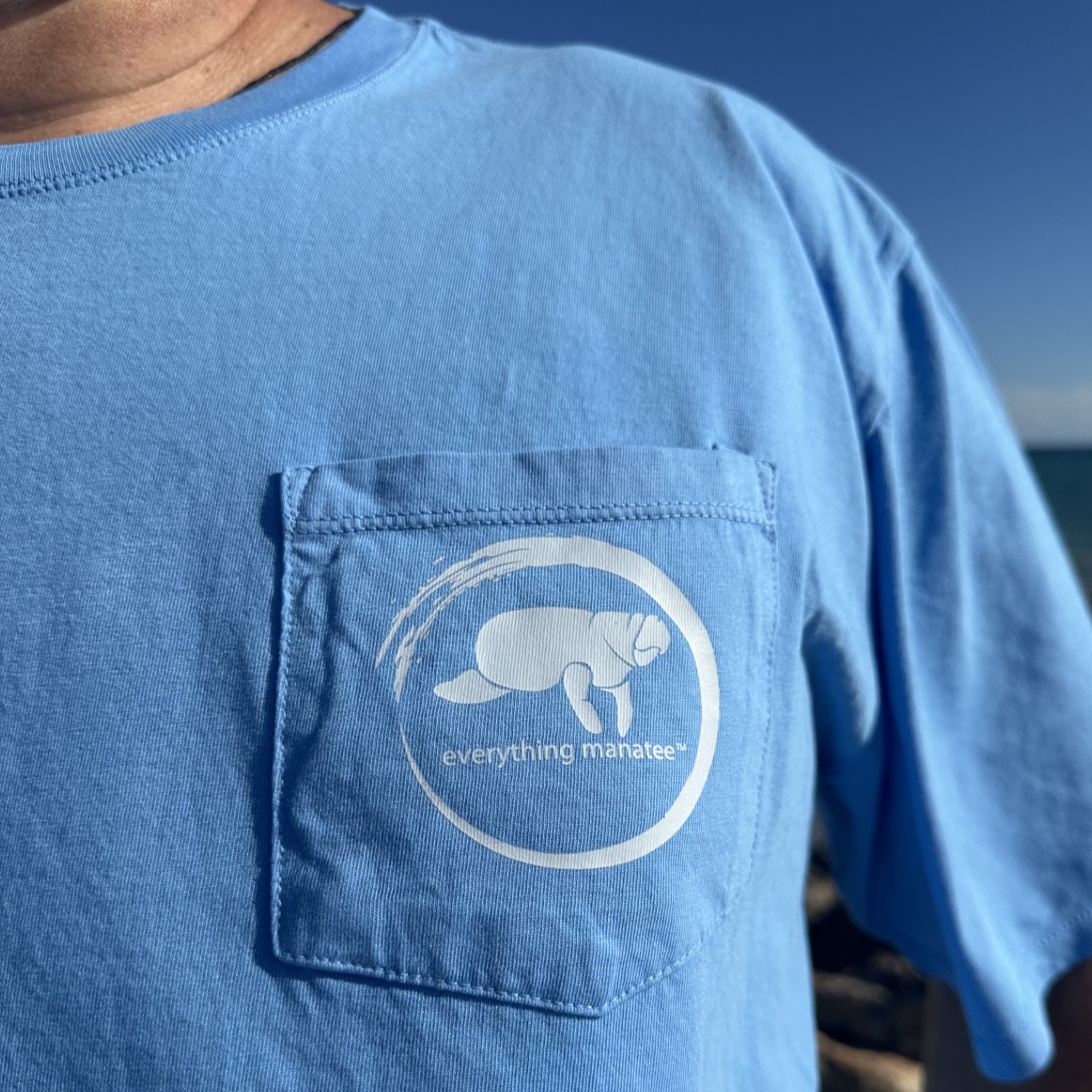 Lifestyle shot of Ocean Blue Manatee Wave Pocket T-Shirt with pocket logo on front