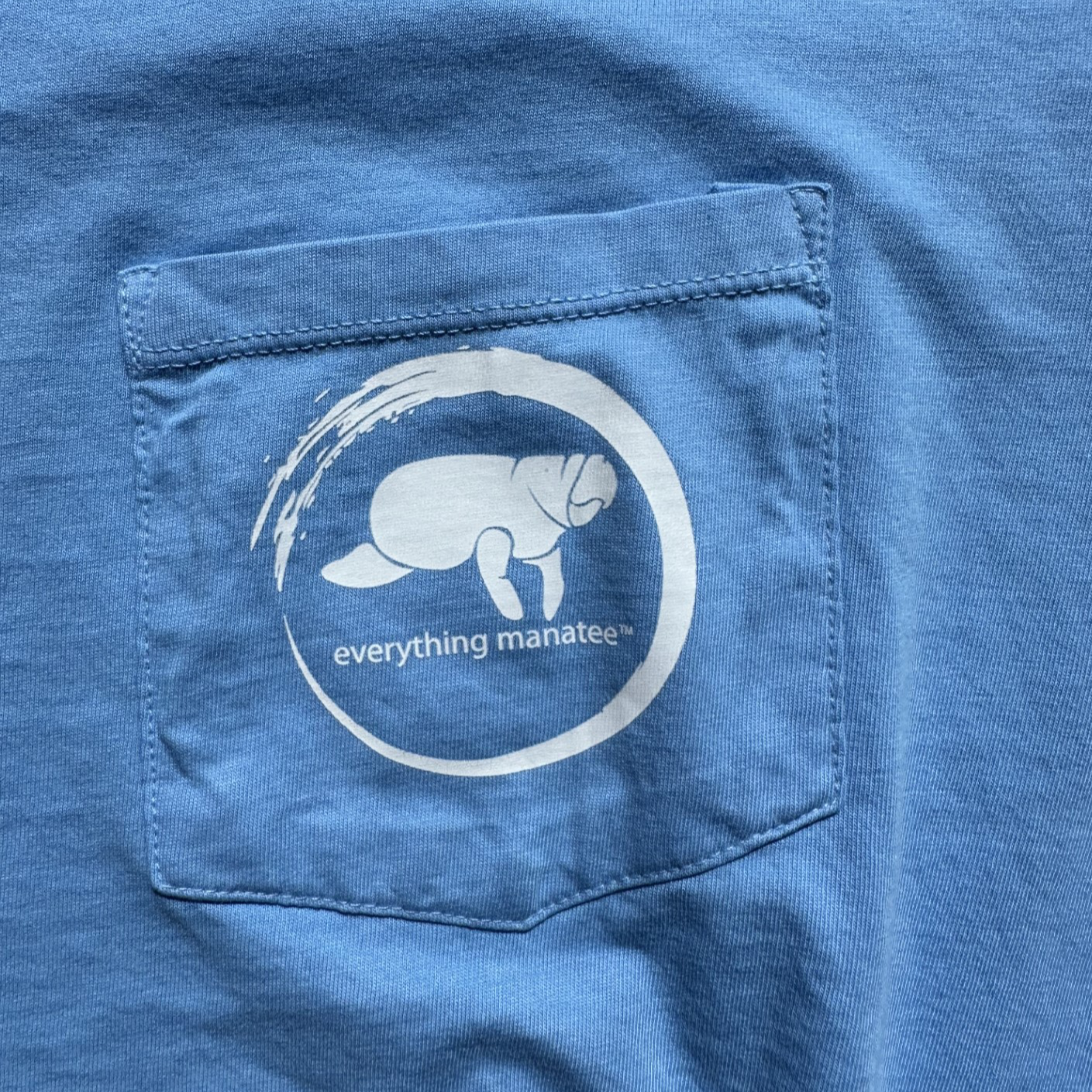 Close-up of pocket logo on Ocean Blue Manatee Wave Pocket T-Shirt