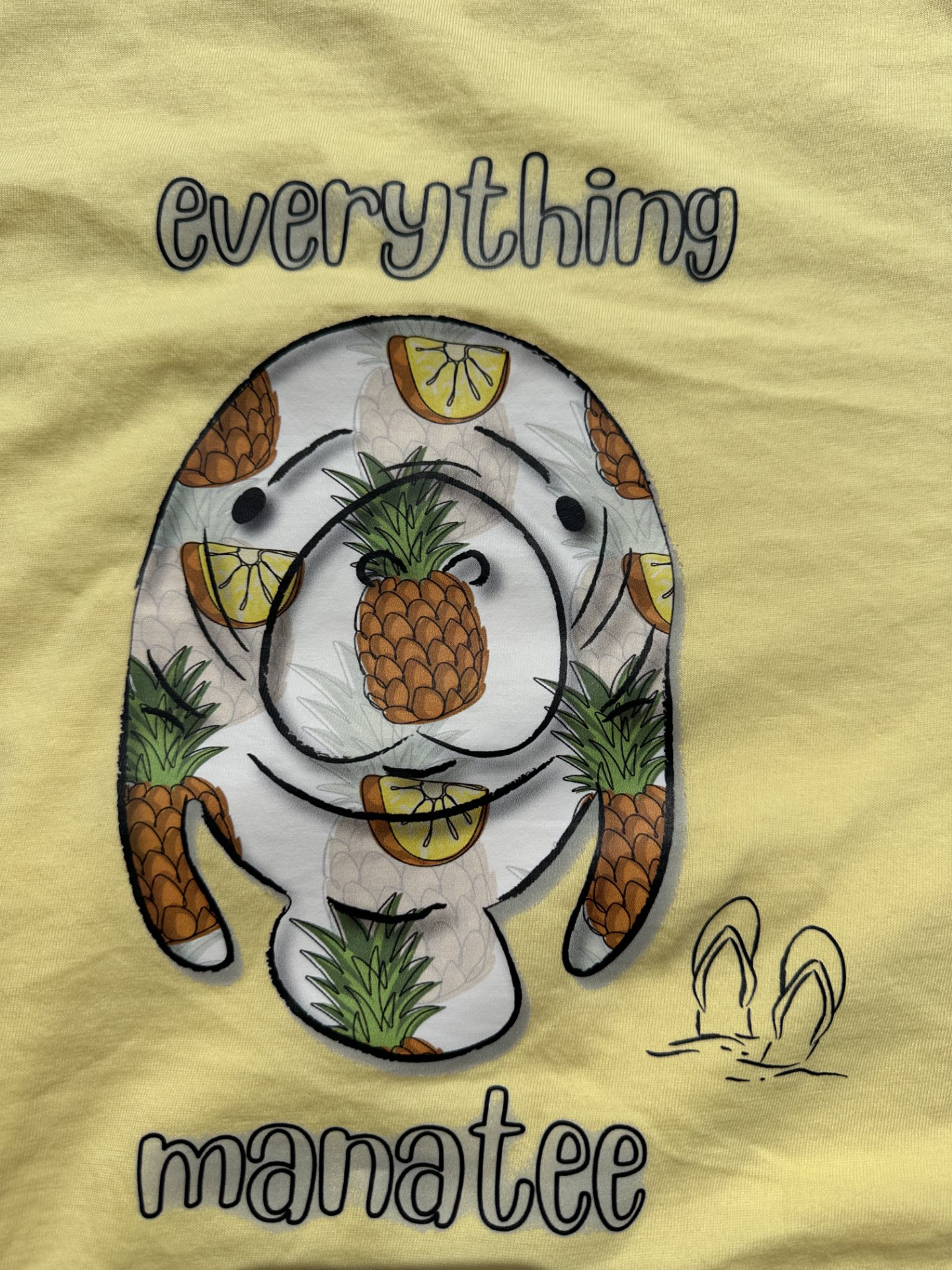 Close-up of back print on Pineapples & Paradise Manatee T-Shirt in banana yellow color