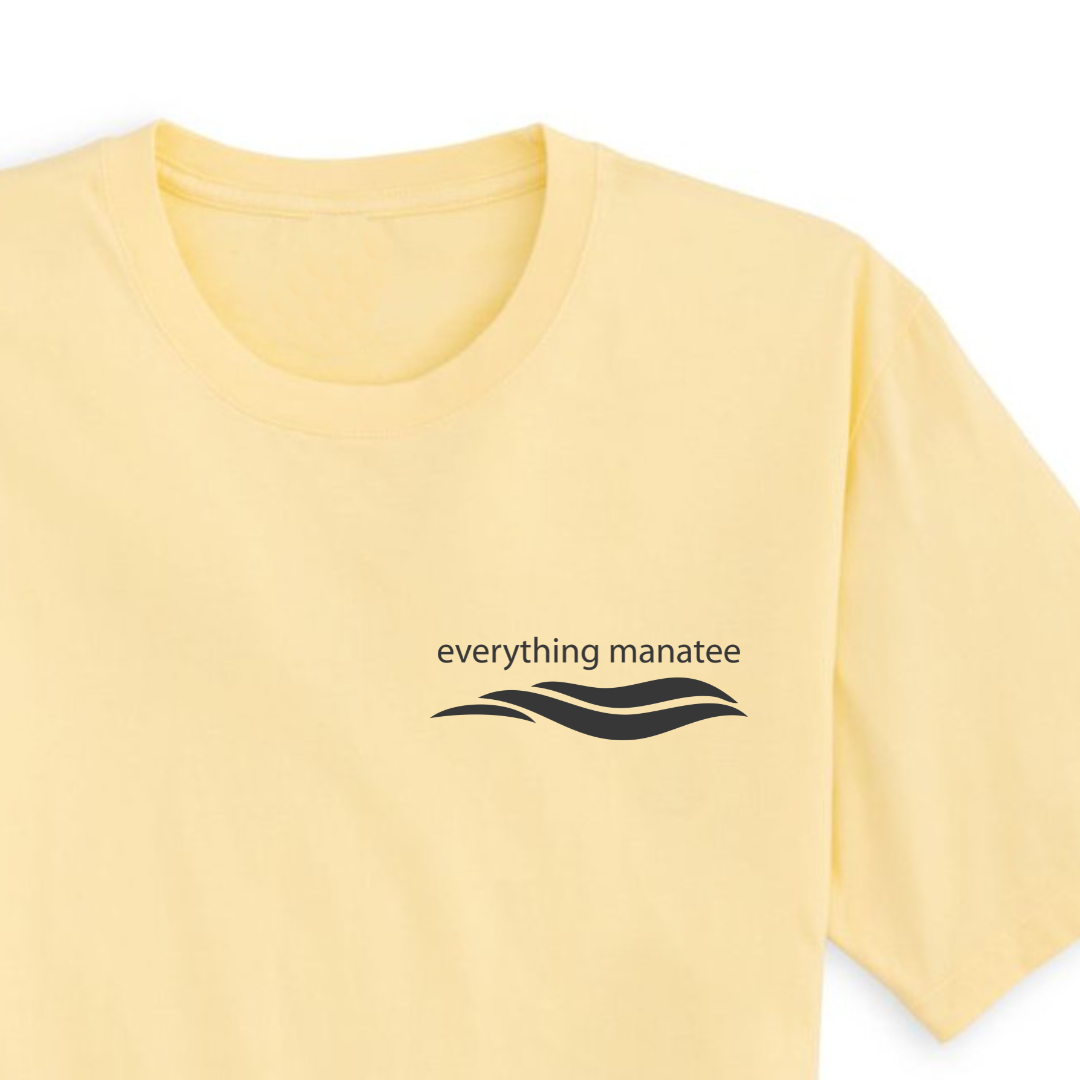 Close-up view of the front chest area of a banana yellow t-shirt with a manatee design. The logo of the shirt is printed on a buttery soft and smooth surface.
