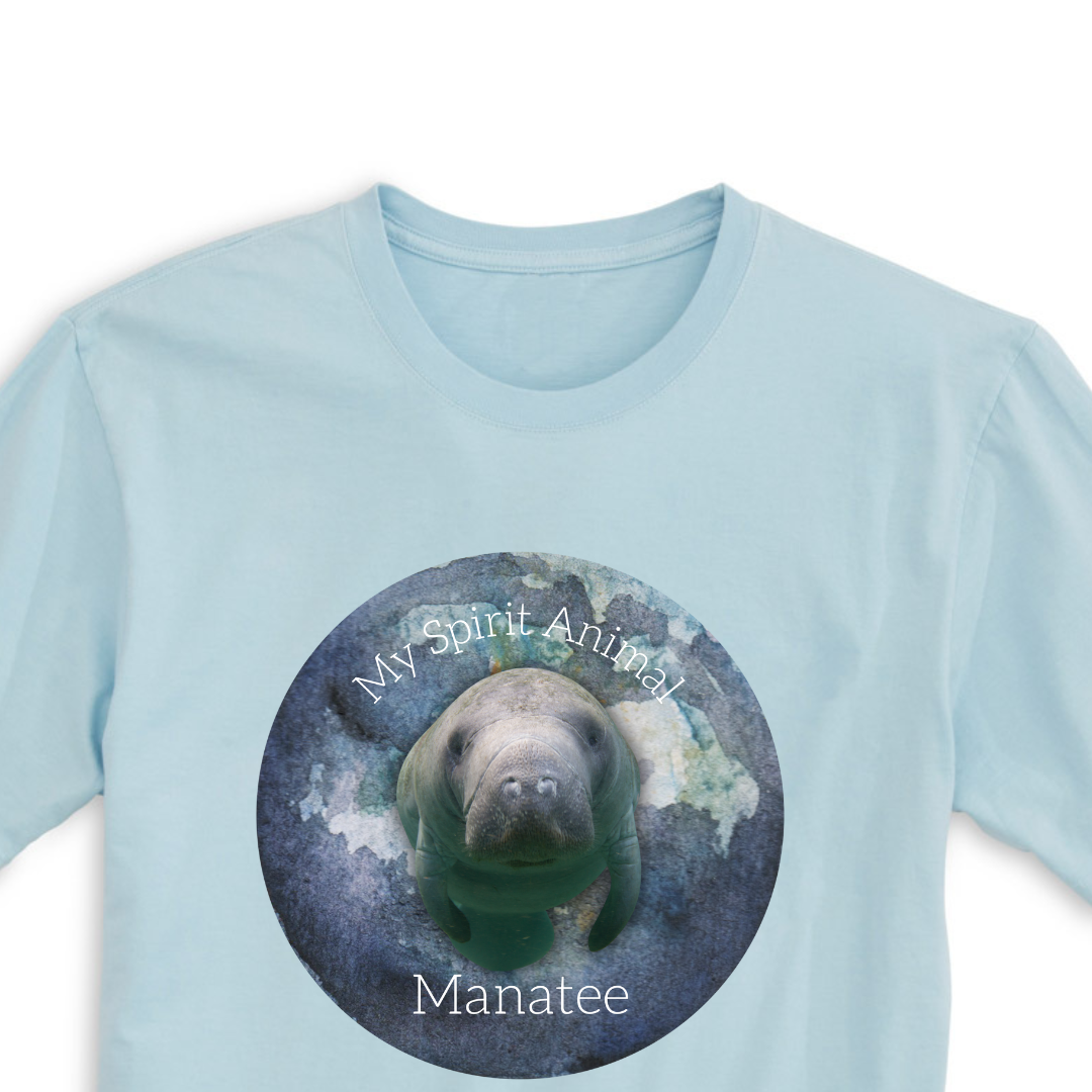 A close-up view of the front print design of the Spirit Animal Manatee T-Shirt in Blue Mist, featuring a delightful illustration of a manatee and the words "Spirit Animal" written in bold lettering above it.