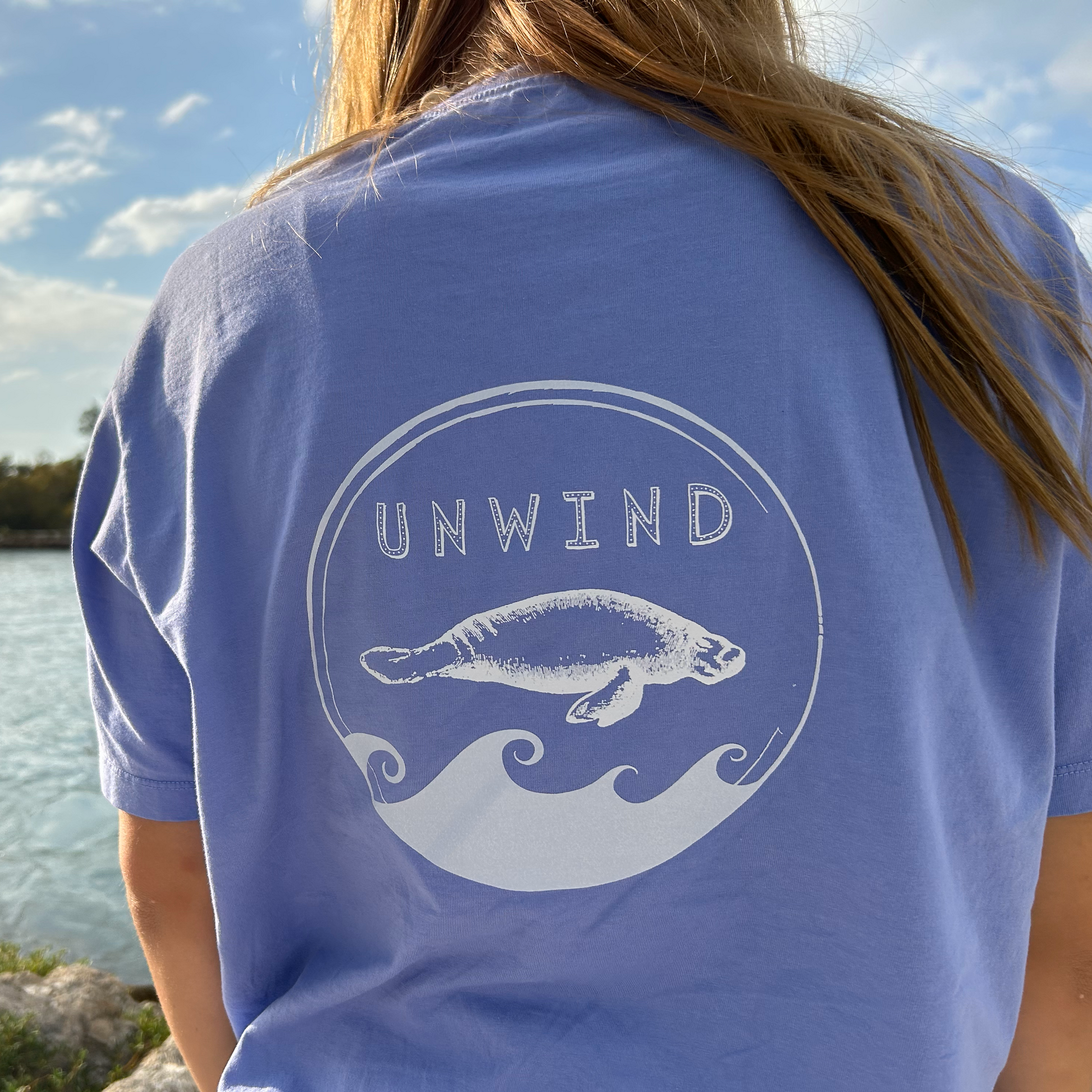 Lifestyle shot of back print on Unwind Manatee T-Shirt in Laid Back Lavender